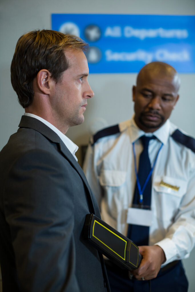 Airport security officer using a hand held metal detector to check a commuter in airport